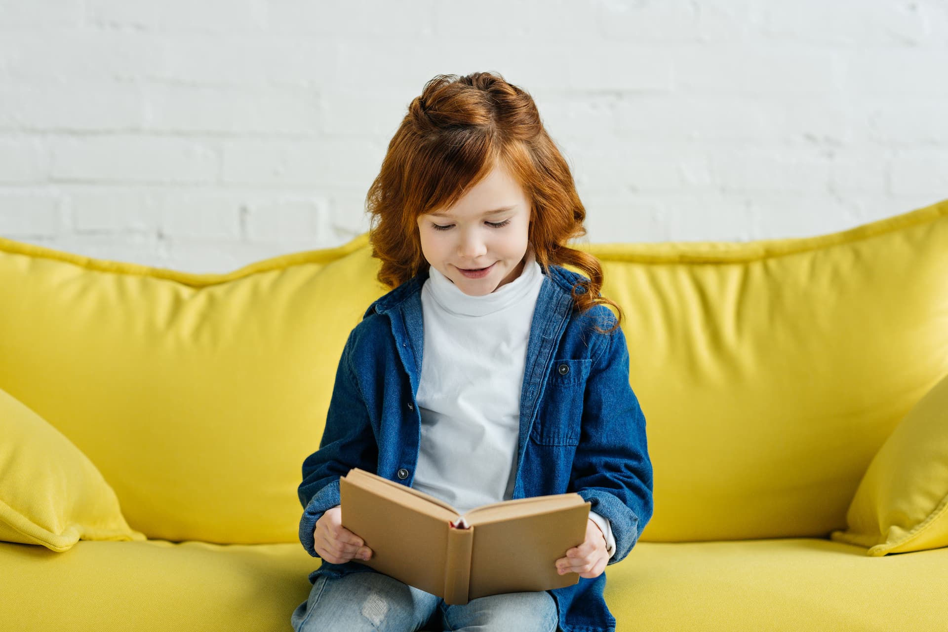 Bambina legge un libro sul divano